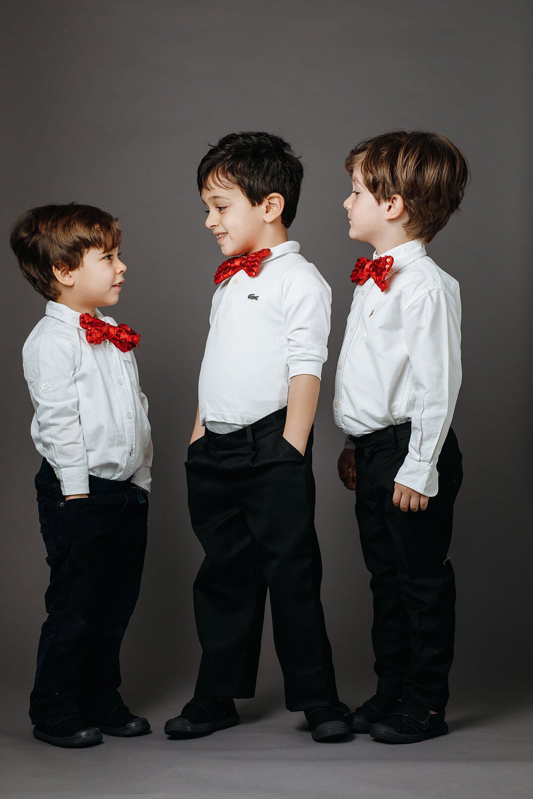 Three boys in white shirts and red sequinned bow ties