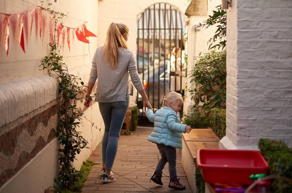 A parent and child walking down the garden passage to the school gate