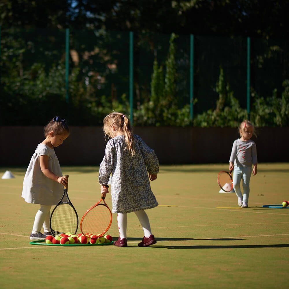 Children with tennis rackets on a court in the sunshine