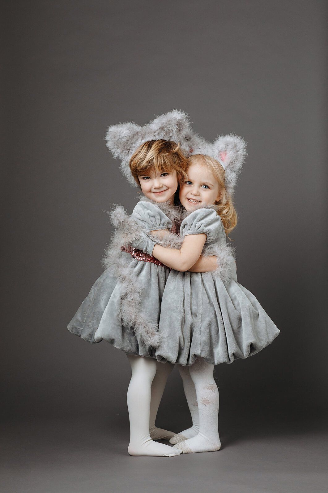 Two children in grey koala costumes hugging