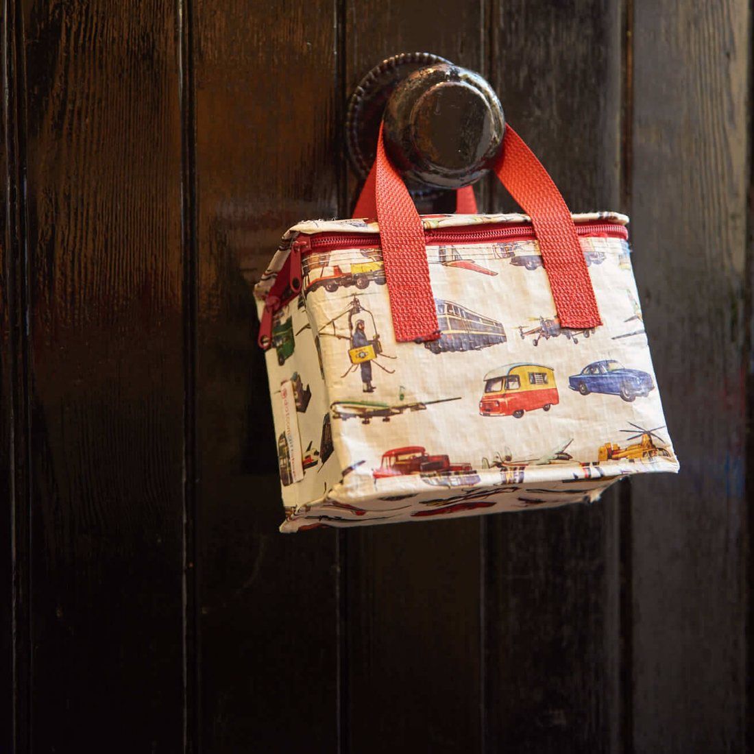 A child’s lunch bag hanging from a dark wooden door