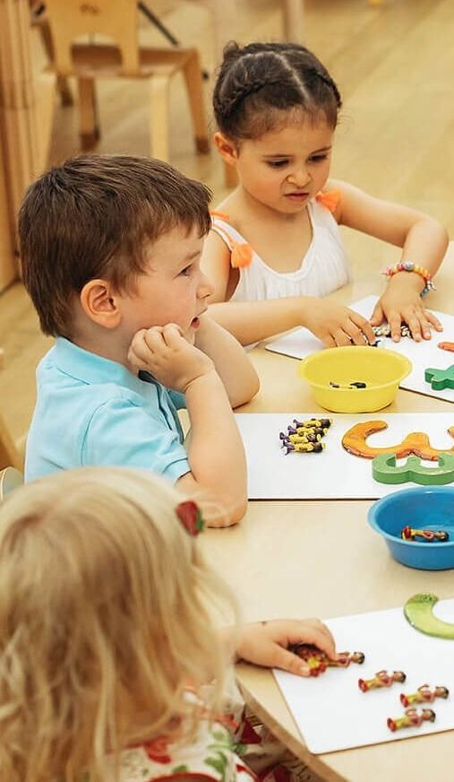 Children working with large numerals and counting toys at a table
