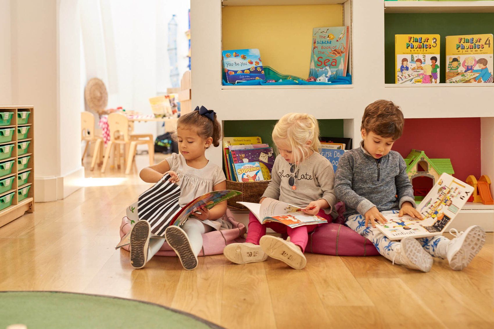 Children sitting on cushions reading picture books